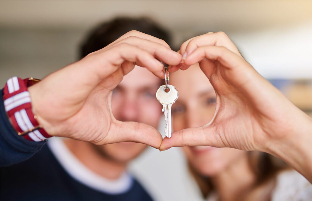 Portrait of a happy young couple proudly displaying the keys to their new house.