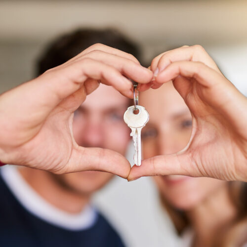 Portrait of a happy young couple proudly displaying the keys to their new house.