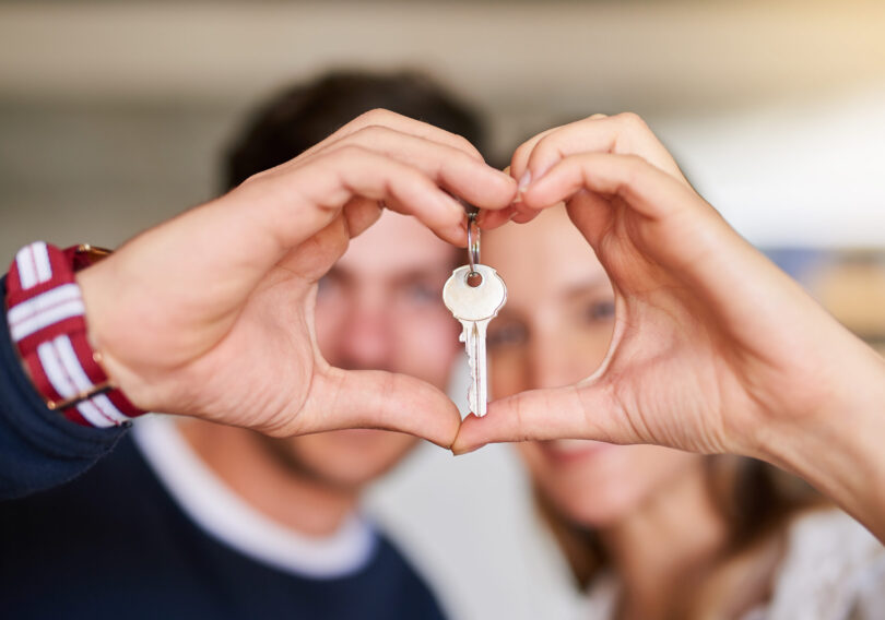 Portrait of a happy young couple proudly displaying the keys to their new house.